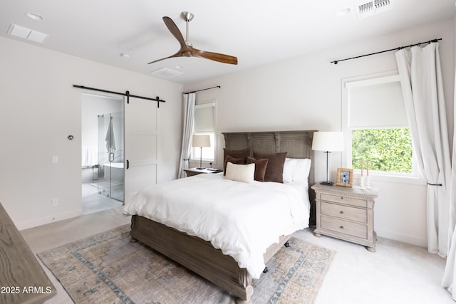 bedroom featuring a barn door, light colored carpet, ensuite bath, and baseboards