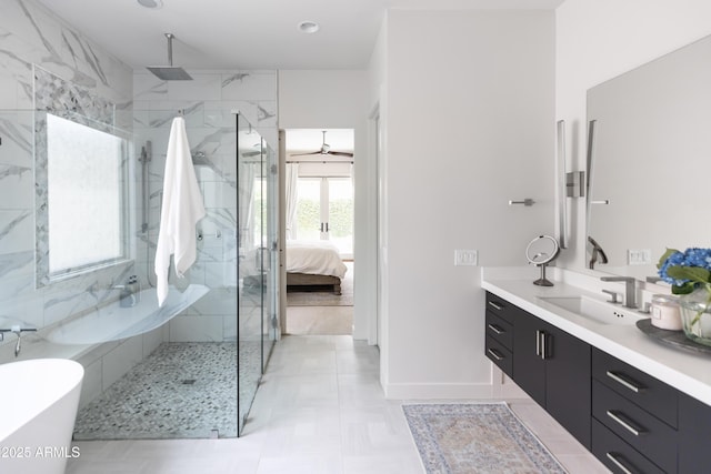ensuite bathroom featuring a marble finish shower, a soaking tub, vanity, and baseboards