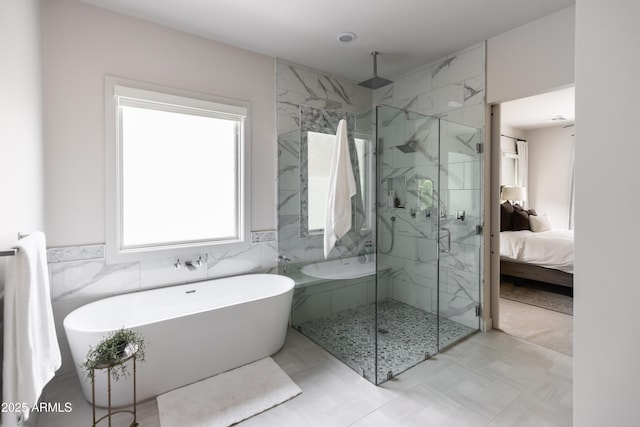 bathroom featuring a marble finish shower, a freestanding bath, connected bathroom, and tile walls