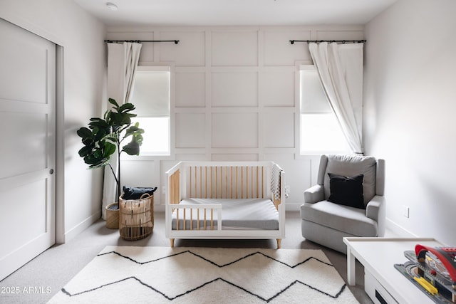 carpeted bedroom featuring a decorative wall and a crib