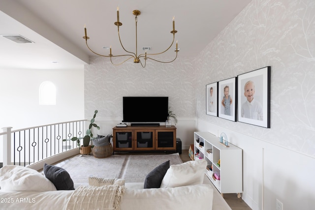 living area featuring wallpapered walls, a chandelier, and a wainscoted wall