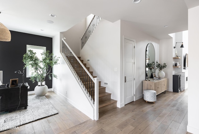 stairway with wood finished floors, baseboards, and recessed lighting