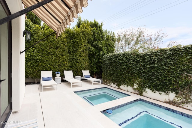 view of swimming pool with an in-ground hot tub and a patio area