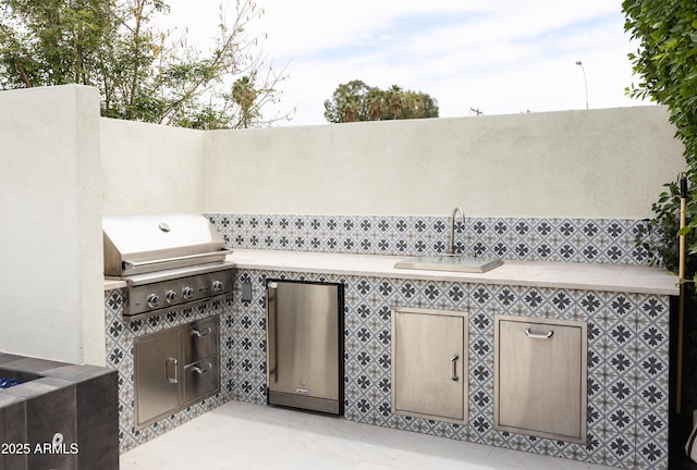 view of patio / terrace with a grill, a sink, an outdoor kitchen, and fence