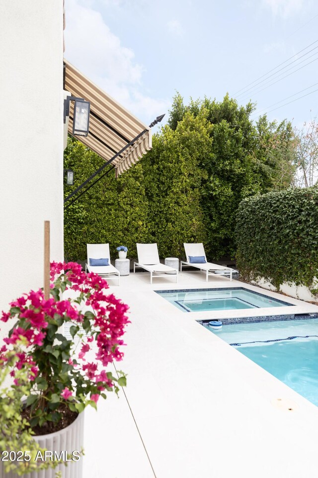 view of pool with a patio and an in-ground hot tub