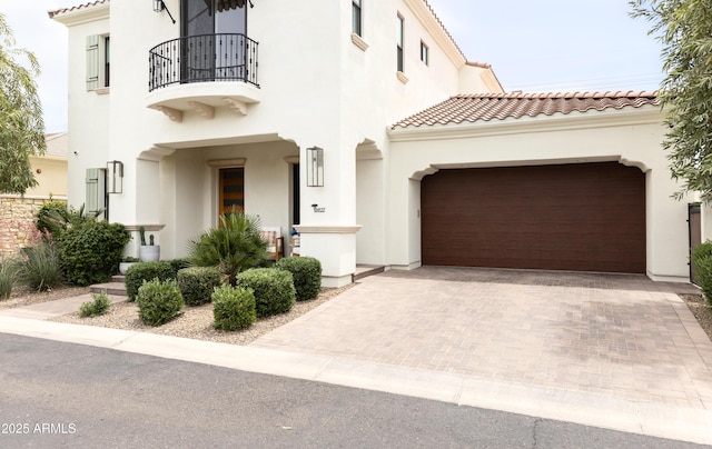 view of front of home featuring a balcony, stucco siding, a tile roof, and decorative driveway