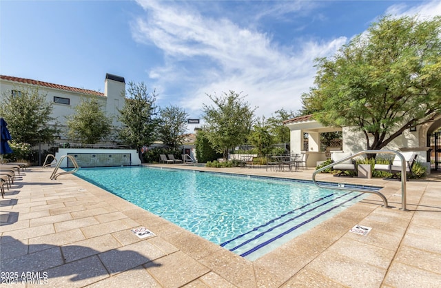 community pool with a patio area and fence