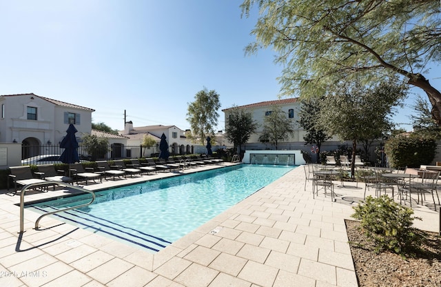 community pool with a patio area, fence, and a residential view