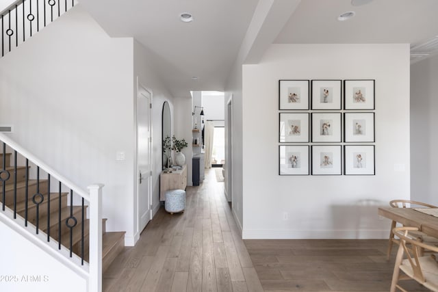 corridor with stairs, wood-type flooring, baseboards, and recessed lighting