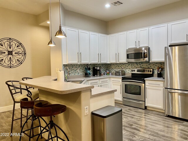 2042 W Periwinkle Way, Chandler, AZ 85248 - kitchen with appliances with stainless steel finishes, a peninsula, a sink, a kitchen breakfast bar, and white cabinetry