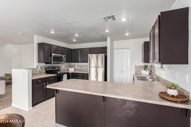 kitchen with sink, kitchen peninsula, appliances with stainless steel finishes, a kitchen breakfast bar, and tasteful backsplash