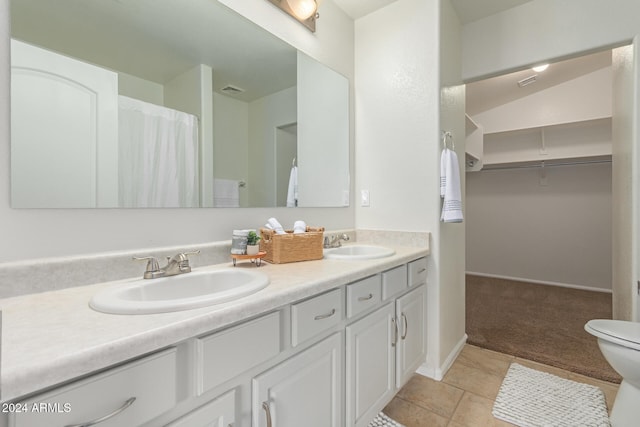 bathroom featuring tile patterned flooring, vanity, and vaulted ceiling