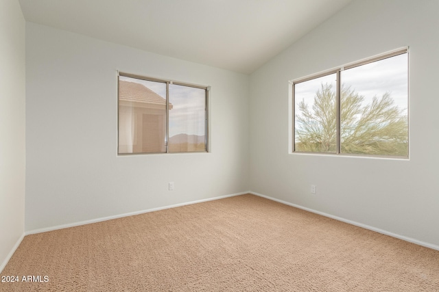 carpeted empty room with lofted ceiling