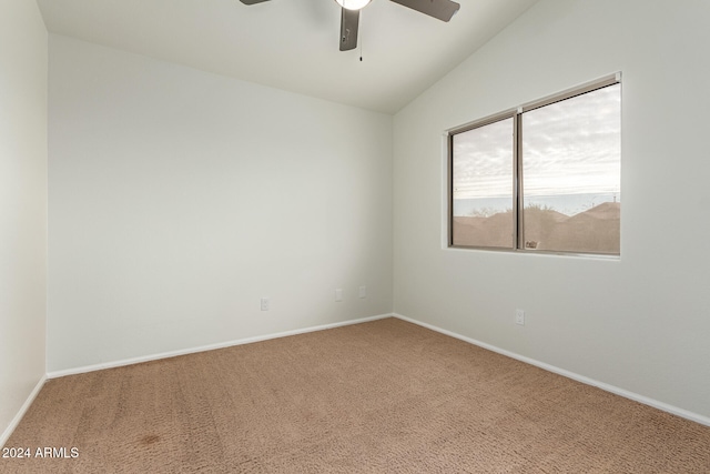 carpeted spare room with ceiling fan and vaulted ceiling