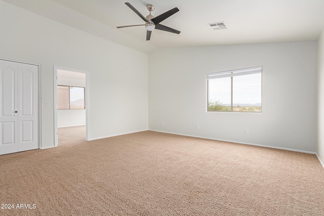 spare room with light colored carpet, lofted ceiling, and ceiling fan