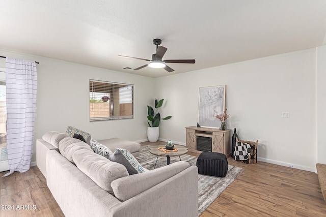 living room with hardwood / wood-style flooring, ceiling fan, and a fireplace