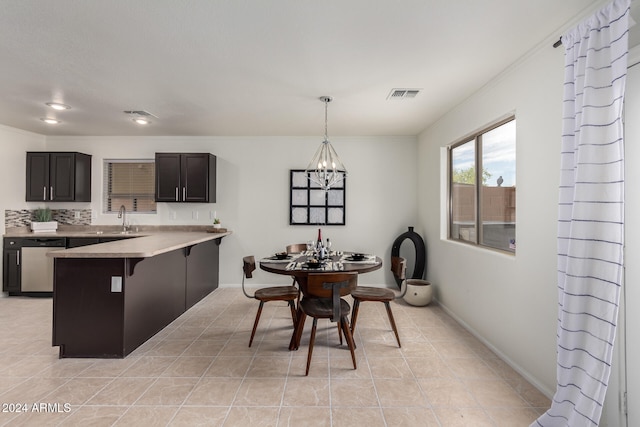 kitchen featuring a notable chandelier, a breakfast bar area, light tile patterned floors, stainless steel dishwasher, and pendant lighting