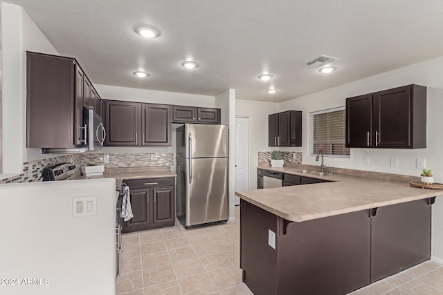 kitchen with stainless steel appliances, kitchen peninsula, decorative backsplash, sink, and a breakfast bar