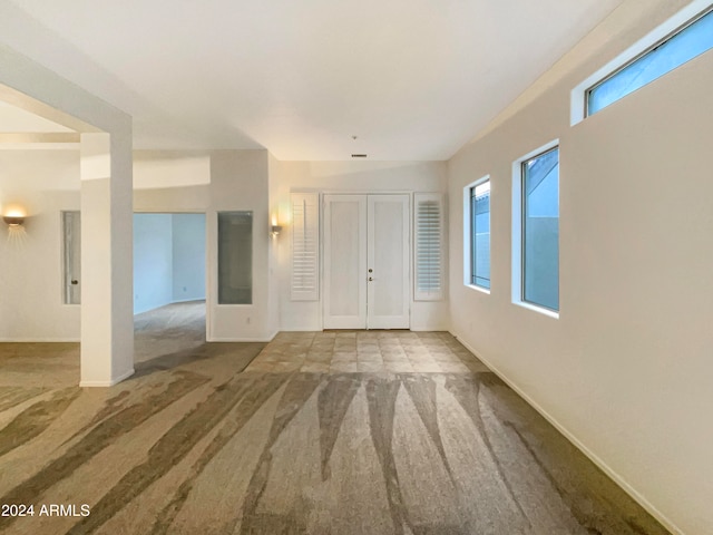 carpeted empty room featuring a wealth of natural light and french doors