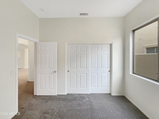 unfurnished bedroom featuring dark colored carpet and a closet