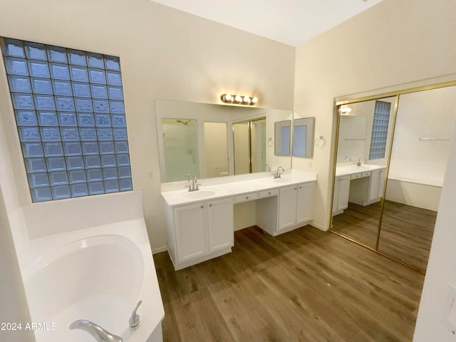 bathroom with hardwood / wood-style floors, vanity, and a tub to relax in