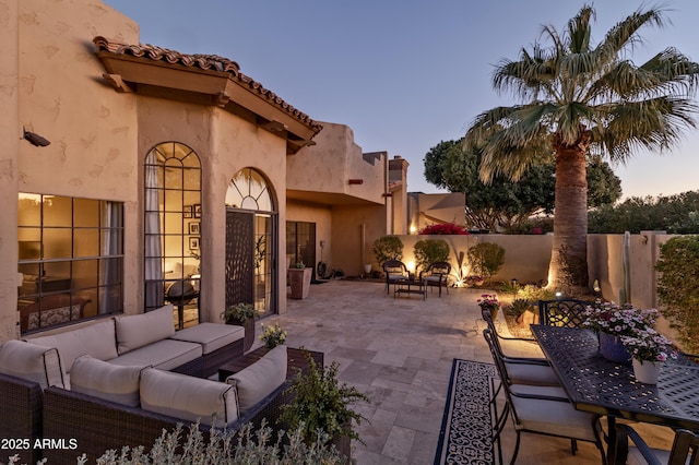 patio terrace at dusk featuring fence and an outdoor hangout area