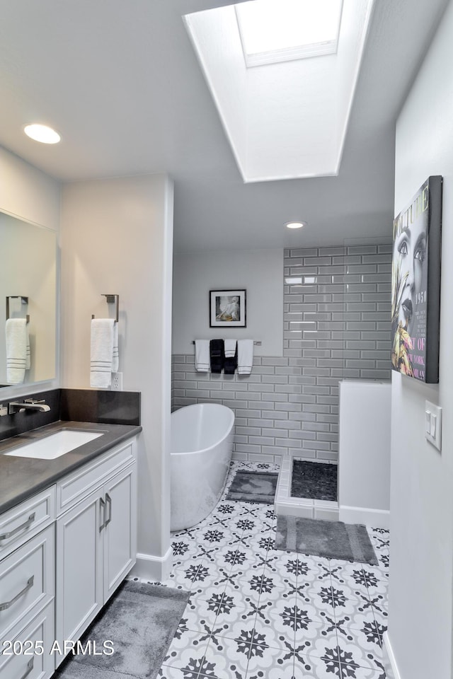 bathroom featuring a freestanding tub, a skylight, vanity, tile walls, and walk in shower