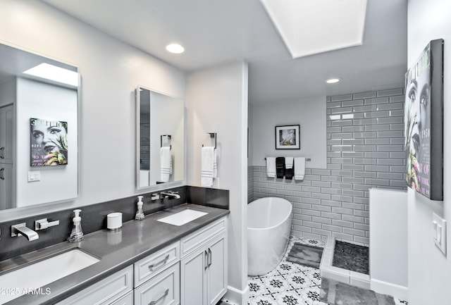 full bath with double vanity, a soaking tub, a sink, and tile walls