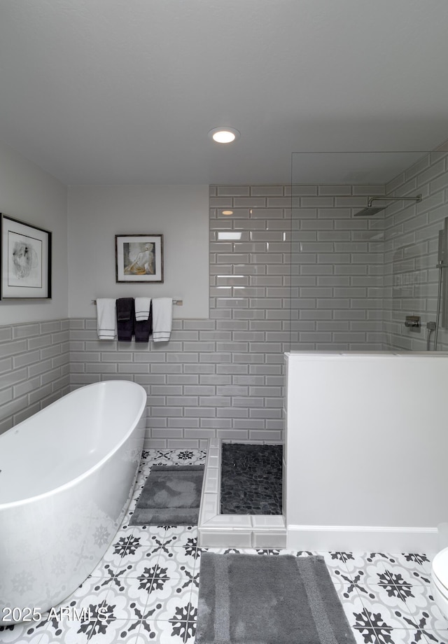 full bath featuring a freestanding tub, a walk in shower, tile walls, and tile patterned floors