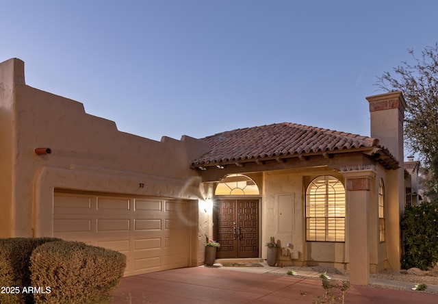 view of front of property featuring a garage, driveway, a chimney, and a tiled roof