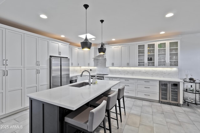 kitchen with beverage cooler, stainless steel appliances, a sink, light countertops, and decorative backsplash