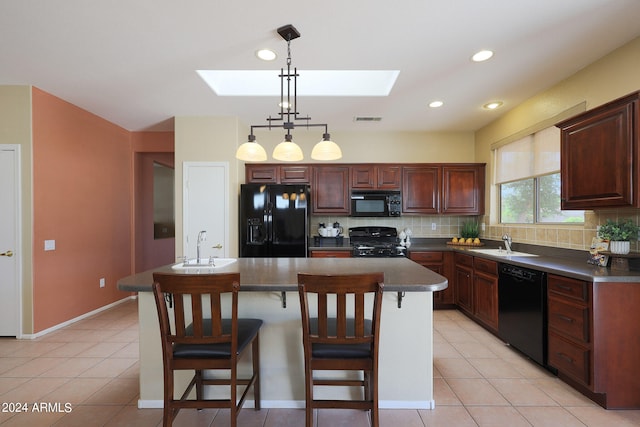 kitchen with backsplash, a breakfast bar area, black appliances, a skylight, and decorative light fixtures