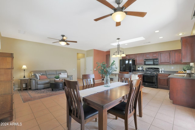 dining area featuring ceiling fan, a skylight, and light tile patterned floors