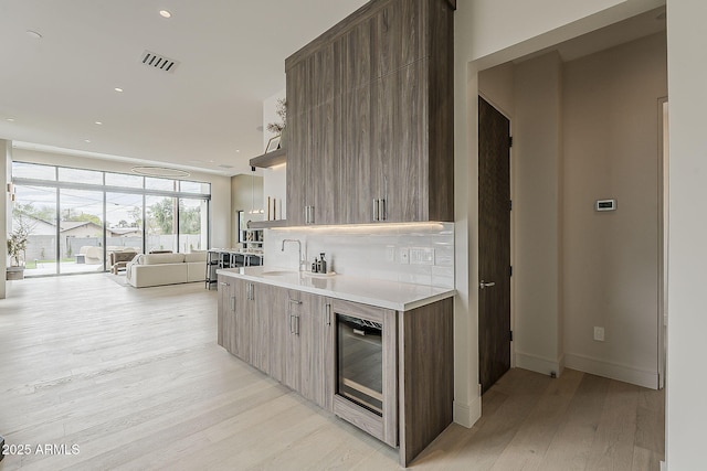 4414 N 29th St, Phoenix, AZ 85016 - kitchen featuring modern cabinets, a sink, light wood-type flooring, expansive windows, and light countertops