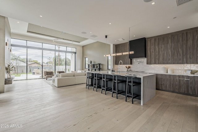 4414 N 29th St, Phoenix, AZ 85016 - kitchen with modern cabinets, a breakfast bar, decorative backsplash, light countertops, and light wood finished floors