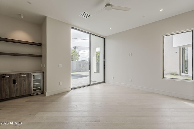 4414 N 29th St, Phoenix, AZ 85016 - unfurnished living room featuring beverage cooler, light wood-style flooring, a ceiling fan, baseboards, and expansive windows