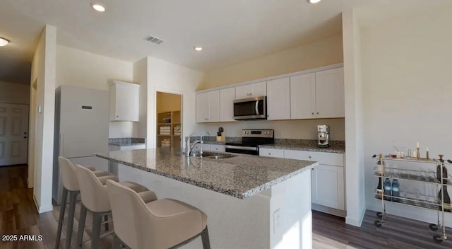 5824 W Willow Ridge Dr, Laveen, AZ 85339 - kitchen with stainless steel appliances, a sink, a center island with sink, dark wood finished floors, and white cabinetry