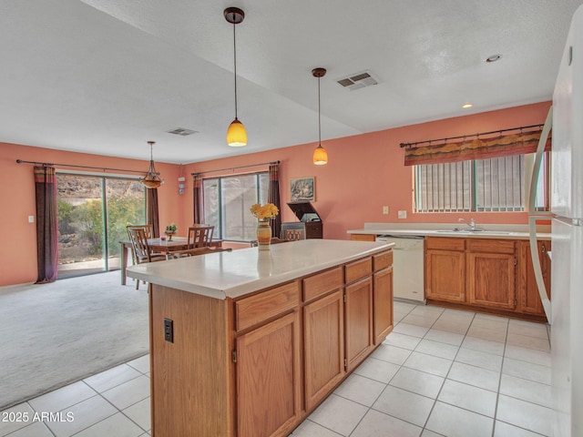 kitchen featuring sink, white appliances, light tile patterned floors, a center island, and decorative light fixtures