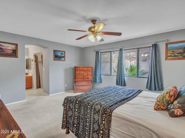 bedroom featuring ensuite bath, light colored carpet, and ceiling fan