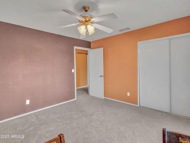 unfurnished bedroom featuring ceiling fan, light colored carpet, and a closet