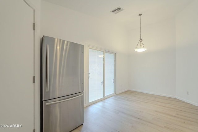 kitchen with stainless steel refrigerator, plenty of natural light, hanging light fixtures, and light wood-type flooring