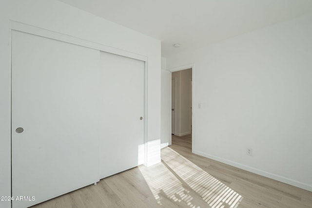 unfurnished bedroom featuring light hardwood / wood-style flooring and a closet