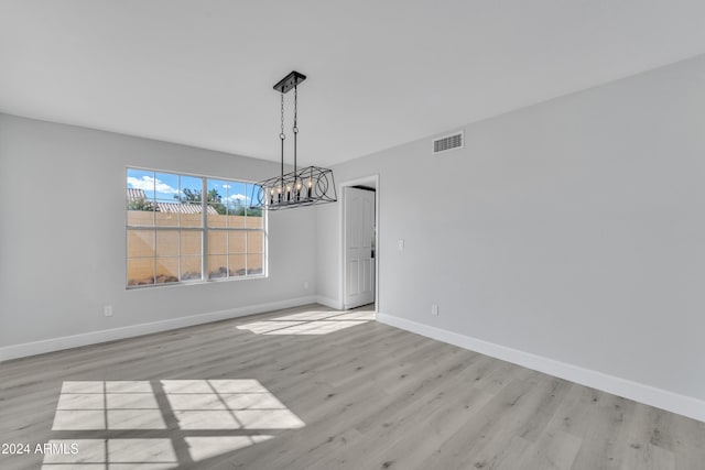 unfurnished dining area with light hardwood / wood-style floors and a notable chandelier