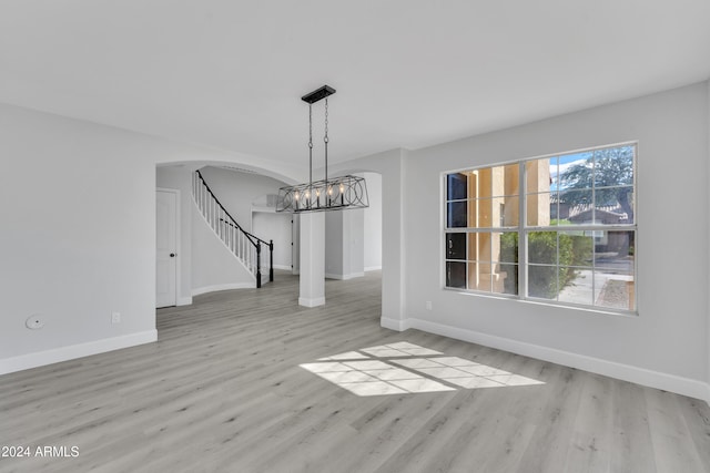 unfurnished dining area with a chandelier and light hardwood / wood-style floors