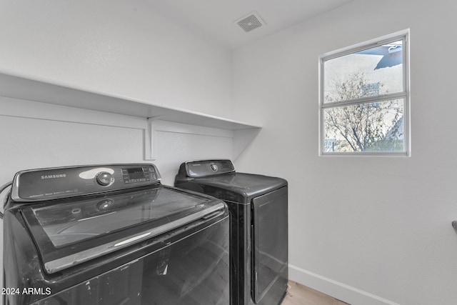 laundry area with light hardwood / wood-style floors and washing machine and clothes dryer