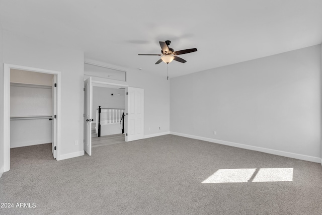 unfurnished bedroom featuring carpet flooring, ceiling fan, a walk in closet, and a closet