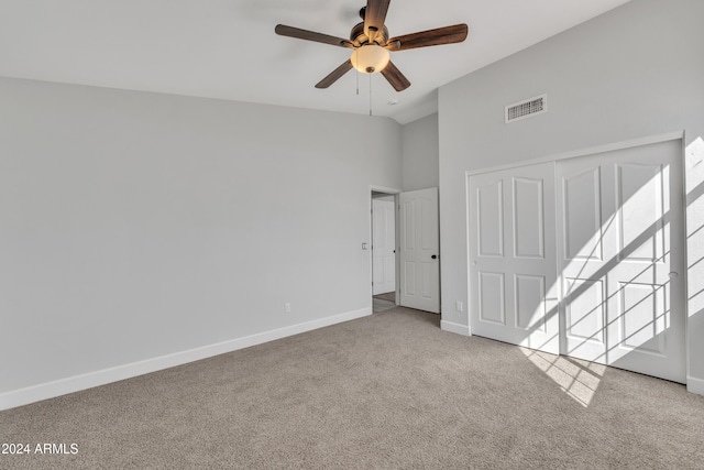 carpeted spare room with ceiling fan and a high ceiling