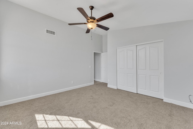 unfurnished bedroom featuring light carpet, a closet, and ceiling fan