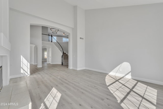 unfurnished living room with a towering ceiling and light hardwood / wood-style flooring