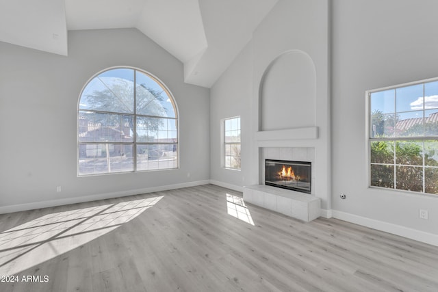 unfurnished living room featuring light hardwood / wood-style flooring, a wealth of natural light, and a tiled fireplace